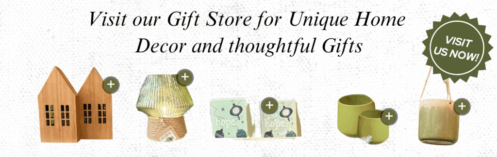 Banner showing home decor items, including wooden house figures, a glass lamp, coasters, and green candle holders, with text promoting a garden centre gift store for unique home decor and gifts.